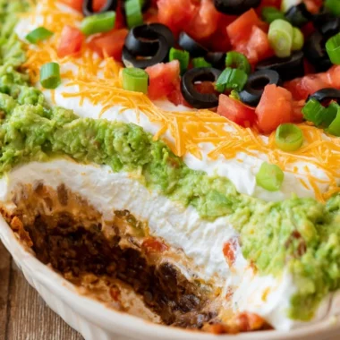 Delicious 7 layer dip with colorful layers of beans, cheese, and toppings.