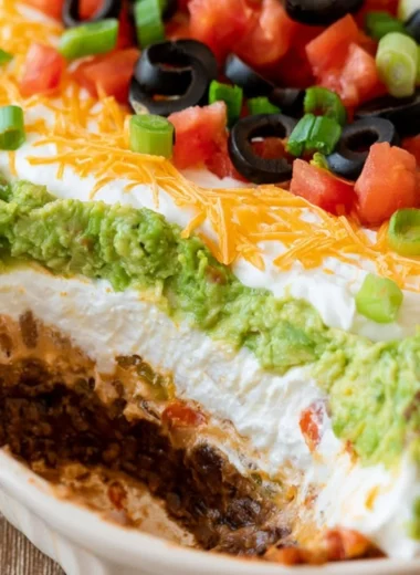 Delicious 7 layer dip with colorful layers of beans, cheese, and toppings.