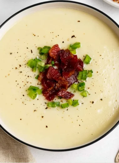 A warm bowl of loaded potato soup topped with cheese and green onions