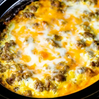 Cheesy sausage hashbrown breakfast on a plate, garnished and ready to eat.