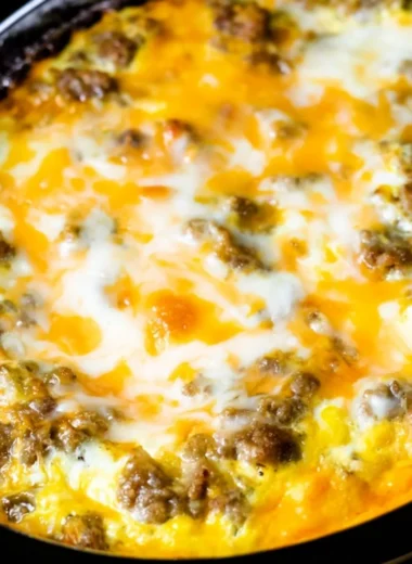 Cheesy sausage hashbrown breakfast on a plate, garnished and ready to eat.