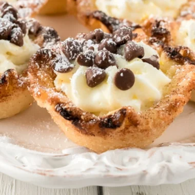 Delicious creamy mini cannoli cups topped with chocolate and powdered sugar.