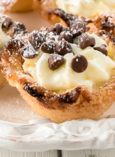 Delicious creamy mini cannoli cups topped with chocolate and powdered sugar.