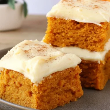 Delicious Paula Deen pumpkin bars topped with cream cheese frosting on a serving plate.