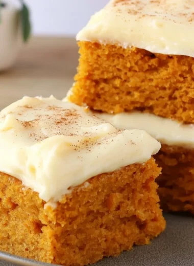 Delicious Paula Deen pumpkin bars topped with cream cheese frosting on a serving plate.