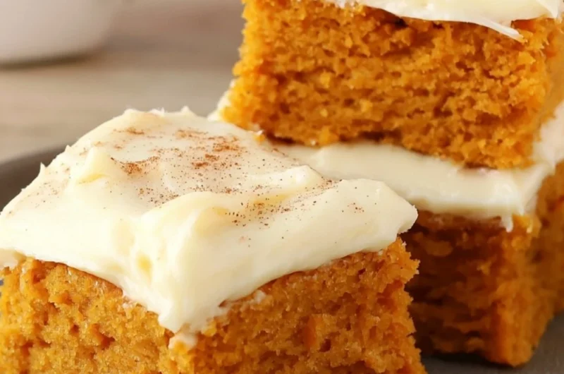 Delicious Paula Deen pumpkin bars topped with cream cheese frosting on a serving plate.
