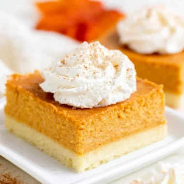 Delicious pumpkin pie bars with buttery shortbread crust on a rustic wooden table