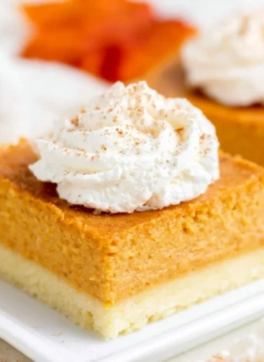 Delicious pumpkin pie bars with buttery shortbread crust on a rustic wooden table