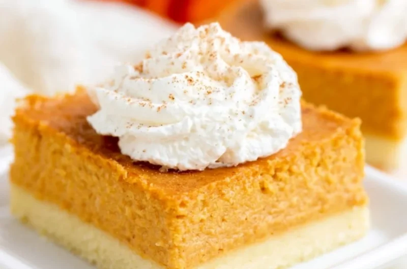 Delicious pumpkin pie bars with buttery shortbread crust on a rustic wooden table