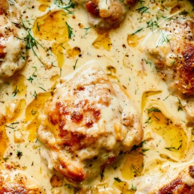 Creamy oven baked chicken thighs served on a plate with herbs