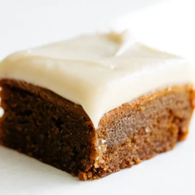 Delicious gingerbread cookie bars with cream cheese frosting on a festive plate.