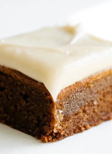 Delicious gingerbread cookie bars with cream cheese frosting on a festive plate.