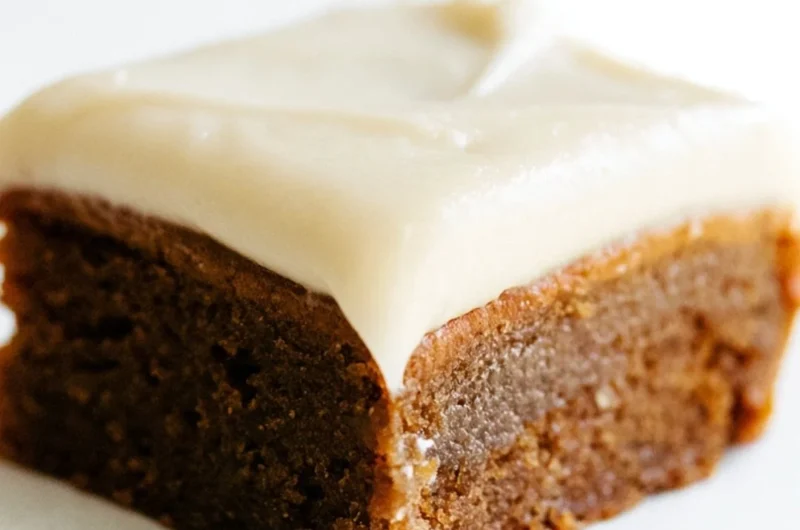 Delicious gingerbread cookie bars with cream cheese frosting on a festive plate.