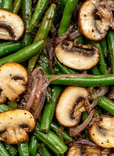Sautéed green beans with mushrooms in a skillet, garnished with herbs.