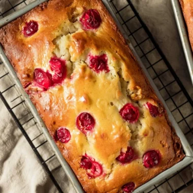 Loaf of Mom's Cranberry Walnut Bread with cranberries and walnuts on a wooden table.