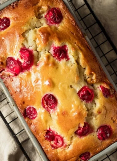 Loaf of Mom's Cranberry Walnut Bread with cranberries and walnuts on a wooden table.