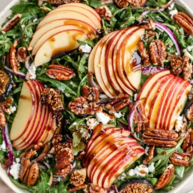 Fresh apple arugula salad with walnuts and vinaigrette on a plate